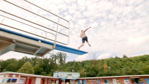 Ein Junge springt vom Turm in das Freibadbecken in Wickede