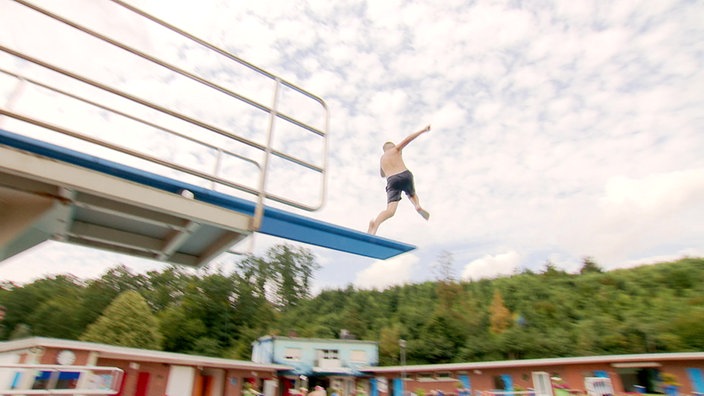 Ein Junge springt vom Turm in das Freibadbecken in Wickede