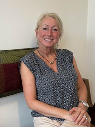 Eine blonde Frau sitzt auf einer Bank.