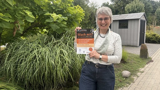 Eine Frau hält ein Plakat für eine Mitmach-Aktion