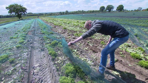 Jannik Buschhoff hält ein Netz auf seinem Feld hoch.