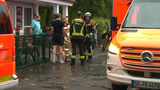 Einsatzkräfte stehen hinter einer Person die in eine Rettungsdecke eingewickelt ist