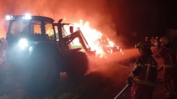 Brennende Strohballen werden von der Feuerwehr gelöscht