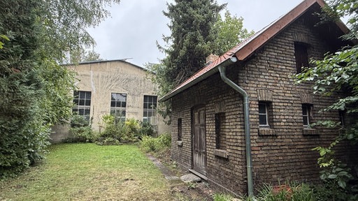 Ein altes Gebäude mit einer Gartenhütte im Vordergrund