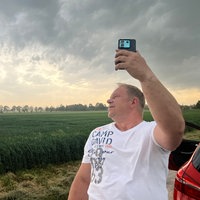 Sturmjäger André Ventrone hält sein Handy in die Luft und streamt für seine Follower. Er ist draußen, im Hintergrund sehen wir Gewitterwolken.