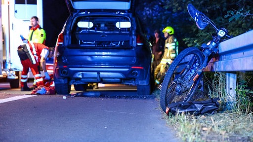 Ein Fahrrad angelehnt an die Leitblanke, dahinter ein Auto und Rettungsdienst 