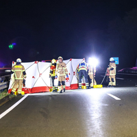 Auf der Fahrbahn der Autobah ist ein weiß-roter Sichtschutz aufgebaut. Davor sind mehrere Feuerwehrleute.