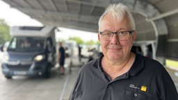 Michael Pomplun vom ADAC Westfalen steht vor einem Wohnwagen, der gewogen wird.