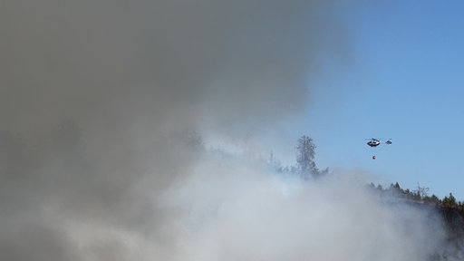 Ein Hubschrauber fliegt direkt in eine große Rauchwolke