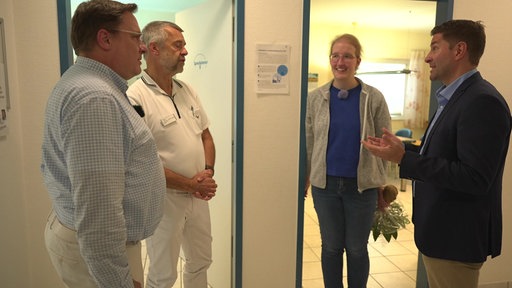 Vier Personen unterhalten sich in einer Arztpraxis
