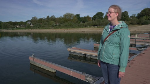 Eine Frau steht auf einem Steeg an einem See