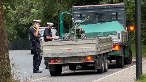 Polizisten stehen an einem Anhänger