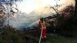 Ein Brand wird von einer Feuerwehrfrau gelöscht.