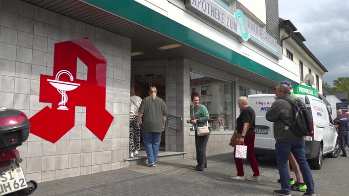 Menschen stehen in einer Schlange vor einer Apotheke