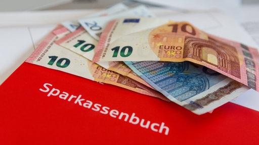 Auf einem Sparbuch von der Sparkasse liegen Geldscheine