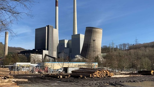 Auf dem Bild ist der Moment zu der Sprengung des Kraftwerkturms zu sehen. Der Turm neigt sich leicht und es ist Rauch von der Explosion zu sehen.