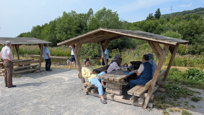 Menschen sitzen in einer Hütte am Fluss 