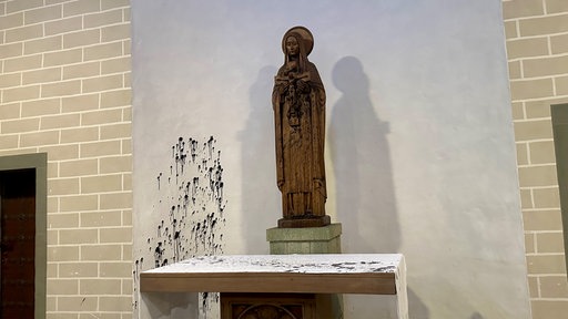 Eine Figur in der Kirche beschmutzt mit schwarzer Farbe