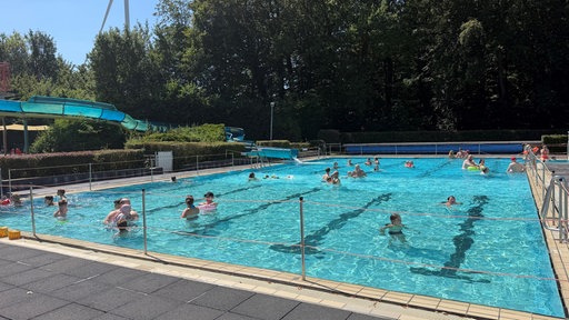 Ein Freibadbecken, in dem viele Menschen schwimmen