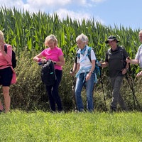 Einige Personen wandern neben einem Maisfeld