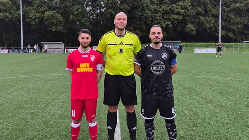 Schiedsrichter Thomas Pidun im Fußballplatz mit zwei Spielern