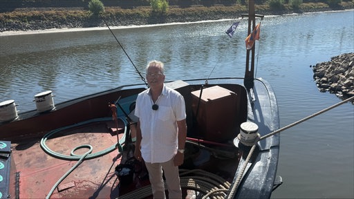 Ein Mann steht auf einem Boot in einem Hafen
