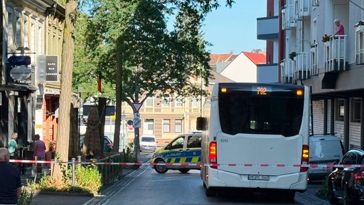 Bus hinter Polizeiabsperrung, Polizeiauto vor Bus, Schaulustige am Straßenrand