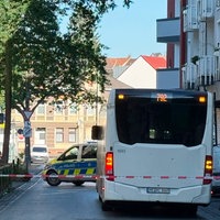 Bus hinter Polizeiabsperrung, Polizeiauto vor Bus, Schaulustige am Straßenrand