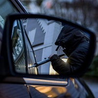 Ein Mann versucht eine Autotür mit einer Metallstange aufzubrechen. Foto gestellt.