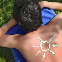 Eine Person trägt eine Sonne gemalt aus Sonnencreme auf dem Rücken