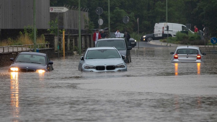Auf einer überfluteten Straße in Stolberg schwimmen vier Autos, zwei haben noch ihre Lichter an