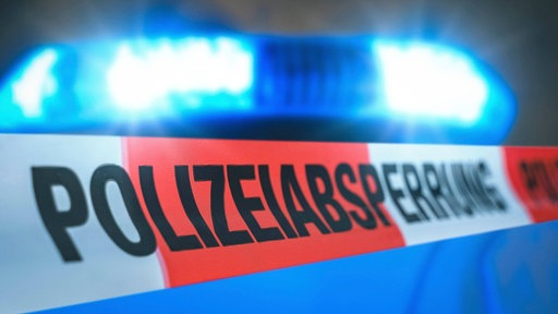 Polizeiabsperrband vor einem Blaulicht