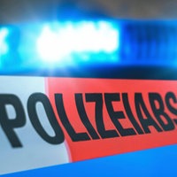 Polizeiabsperrband vor einem Blaulicht