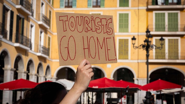 Schild auf dem "Tourists Go Home" steht