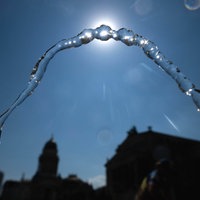 Die Wasserfontäne eines Trinkbrunnens vor blauem Himmel und strahlender Sonne