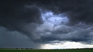 Dunkle Wolken ziehen sich über ein Feld am Himmel