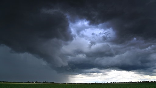 Dunkle Wolken ziehen sich über ein Feld am Himmel