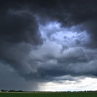 Dunkle Wolken ziehen sich über ein Feld am Himmel