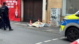 eine Plane und vier Warnhüte verdecken den Rucksack