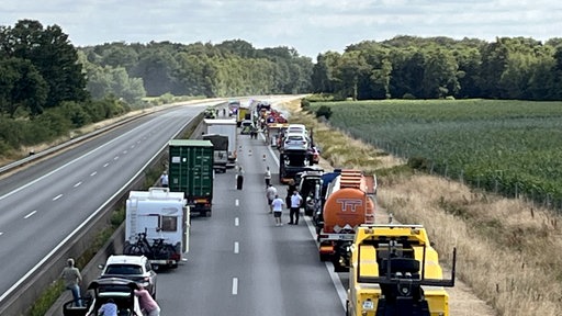 Ein Stau auf der A31, im Hintergrund ist die Feuerwehr beim Löscheinsatz.