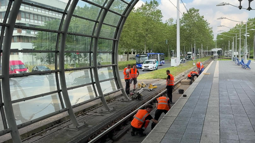 Personen in orangenen Warnwesten stehen auf dem Gleis.