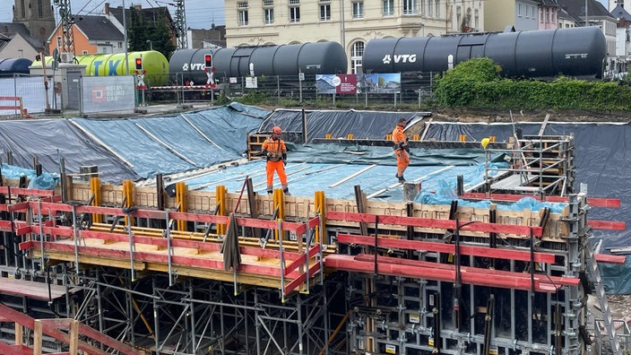 Ein großes Baugerüst vor Bahngleisen.