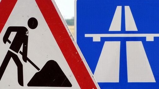 Ein Baustellenschild ist vor einem Autobahnschild platziert.