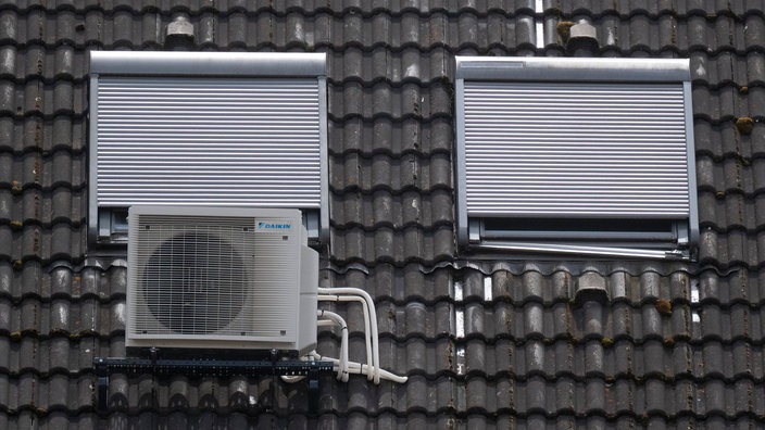 Eine Klimaanlage an einem mit Jalousie verdunkelten Dachfenster
