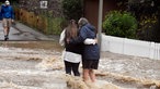 Zwei Frauen halten sich in den Armen während sie durch eine überflutete Straße waten