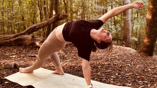 Eine Frau macht Yoga im Wald.