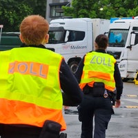 Zwei Beamte der Zollfahnund laufen im Rahmen einer Konrolle im Rheinland auf eine Reihe von geparkten Lkw zu
