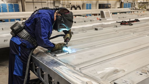 Ein Siemens Mitarbeiter schweißt an einem Bauteil für einen neuen Zug. 
