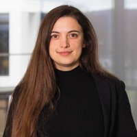Nadine Michollek Eine Frau mit schwarzem Oberteil lehnt an einem Geländer und blickt in die Kamera