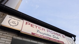Leuchtreklame an der Fassade von "Peter Pomms Puszettenstube" in Duisburg